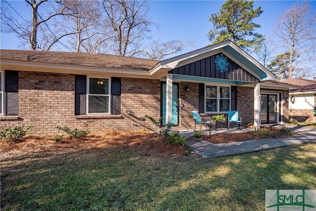 ranch-style house with brick siding, board and batten siding, covered porch, and a front yard