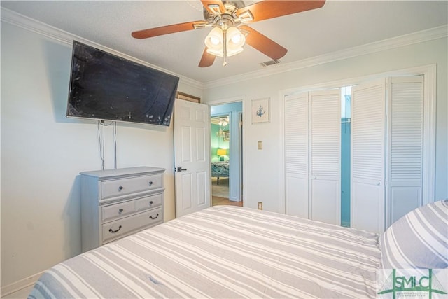 bedroom with crown molding, visible vents, a closet, and ceiling fan