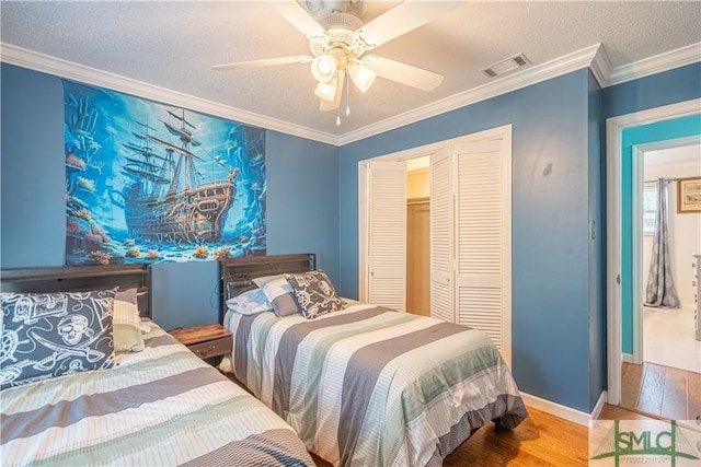 bedroom featuring visible vents, a textured ceiling, wood finished floors, and crown molding