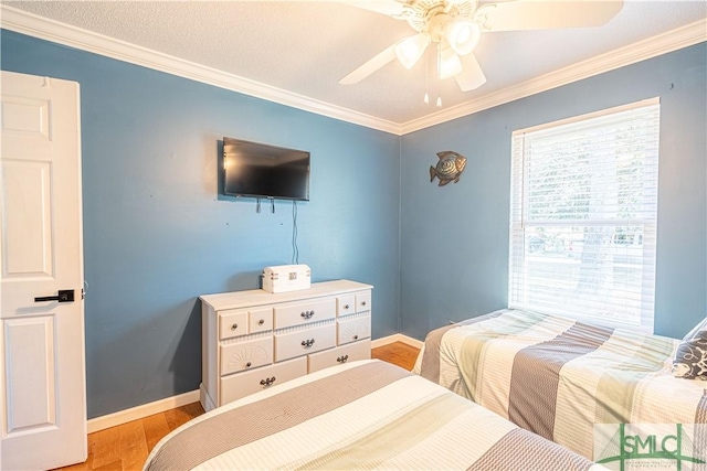 bedroom featuring baseboards, wood finished floors, and crown molding