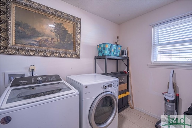 laundry room with laundry area, light tile patterned flooring, baseboards, and washer and clothes dryer