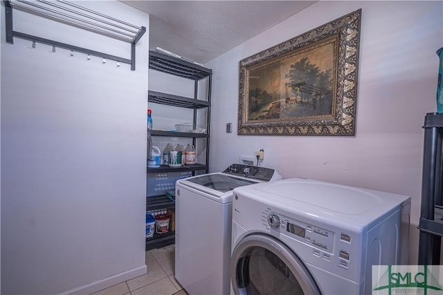 laundry area featuring a textured ceiling, light tile patterned flooring, laundry area, and washer and clothes dryer