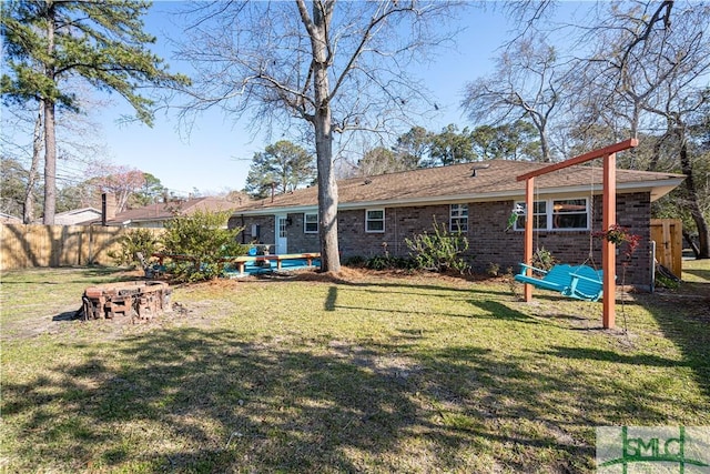 rear view of house with brick siding, a lawn, and fence