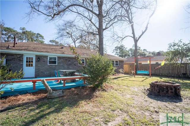 back of house featuring a yard, a fire pit, brick siding, and fence