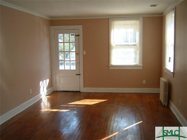 entryway with visible vents, wood-type flooring, ornamental molding, and radiator heating unit