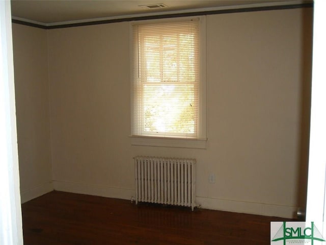 empty room featuring baseboards, radiator, and dark wood-style floors