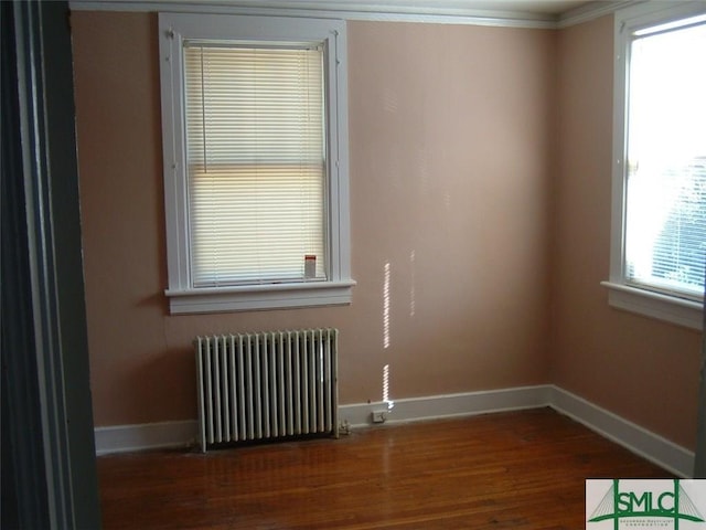 empty room featuring radiator, wood finished floors, and baseboards