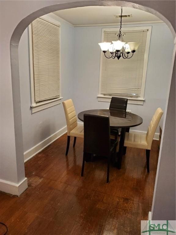 dining space featuring visible vents, dark wood finished floors, arched walkways, an inviting chandelier, and baseboards