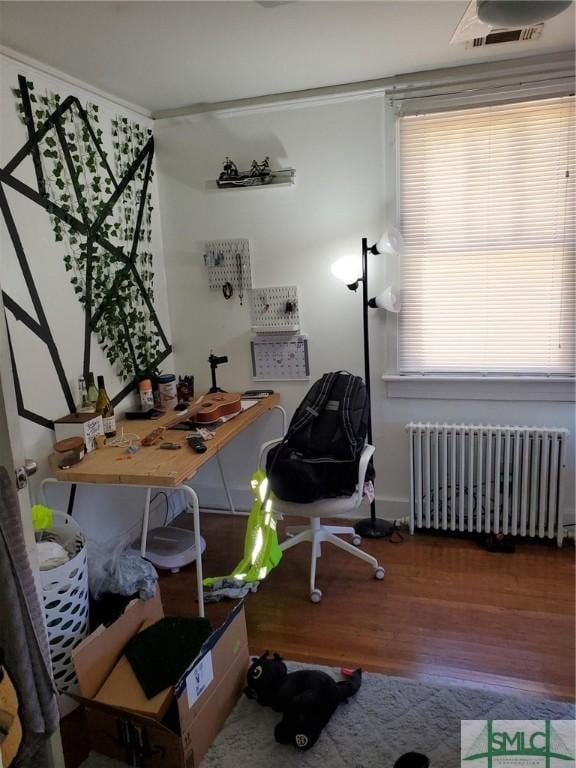 office area with visible vents, wood finished floors, and radiator heating unit