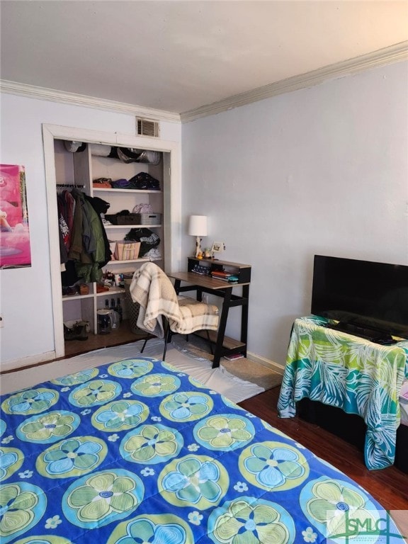 bedroom featuring visible vents, ornamental molding, wood finished floors, a closet, and baseboards