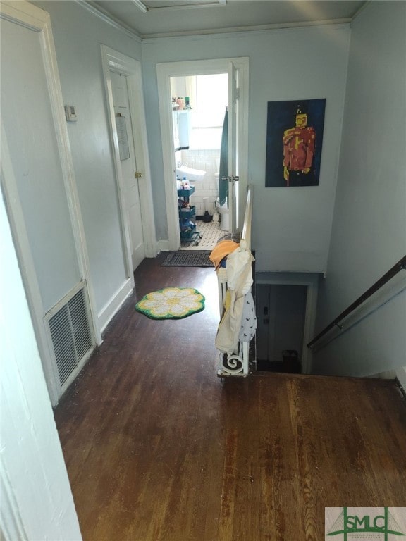 corridor with visible vents, ornamental molding, baseboards, and wood finished floors