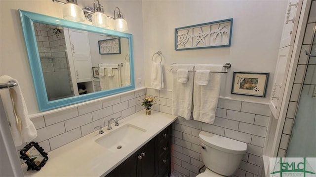 full bathroom with a wainscoted wall, toilet, vanity, tile walls, and a shower