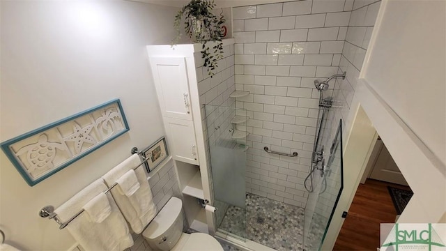 full bath featuring wood finished floors, toilet, and a stall shower