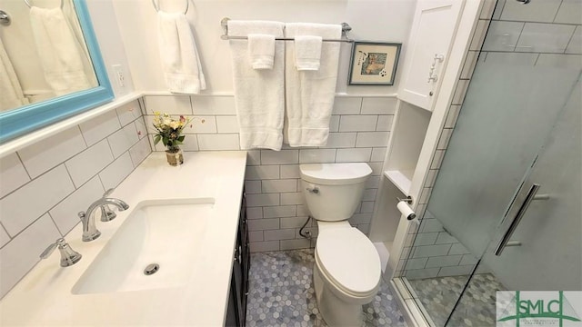 full bath with vanity, toilet, tile walls, and a shower with shower door