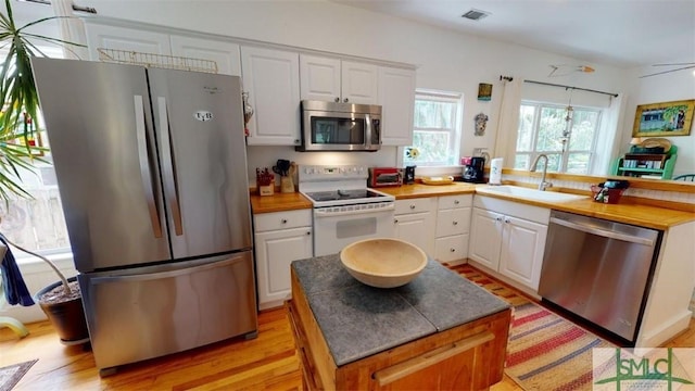 kitchen featuring a sink, appliances with stainless steel finishes, a peninsula, and white cabinetry