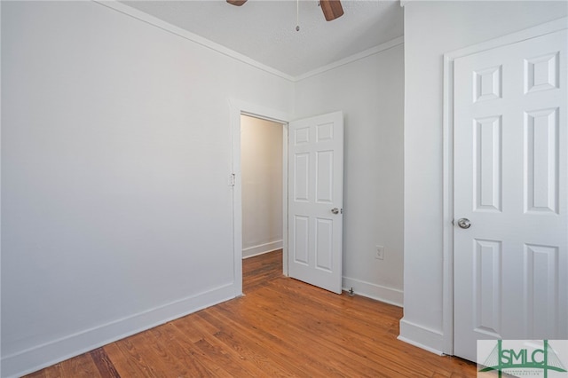 unfurnished bedroom featuring ceiling fan, baseboards, wood finished floors, and ornamental molding