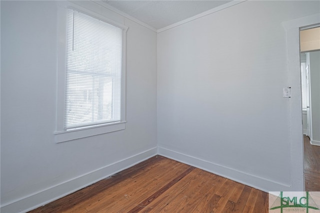 unfurnished room featuring crown molding, baseboards, and wood finished floors