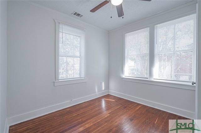 empty room featuring baseboards, dark wood-style floors, visible vents, and a healthy amount of sunlight