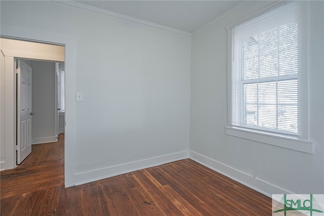 empty room with dark wood-type flooring, baseboards, and ornamental molding