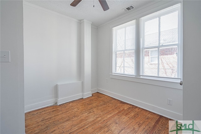 empty room with baseboards, light wood-style floors, visible vents, and a textured ceiling