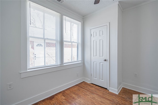 unfurnished bedroom with baseboards, a textured ceiling, light wood-style flooring, and crown molding