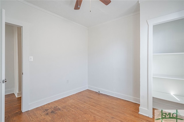 spare room with ceiling fan, baseboards, wood finished floors, and crown molding