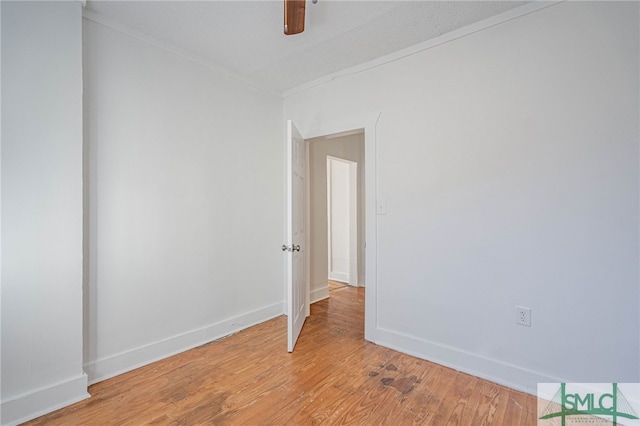 spare room featuring light wood-type flooring, baseboards, and crown molding