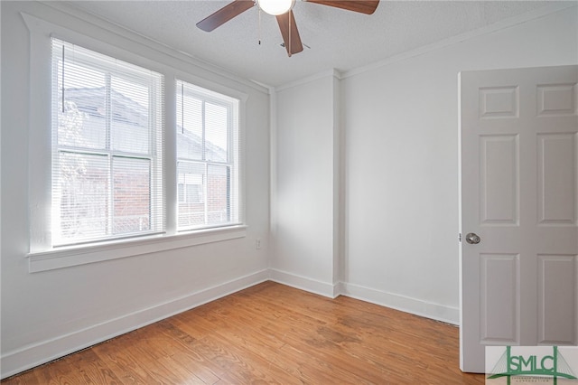 spare room featuring baseboards, light wood-style flooring, ceiling fan, ornamental molding, and a textured ceiling