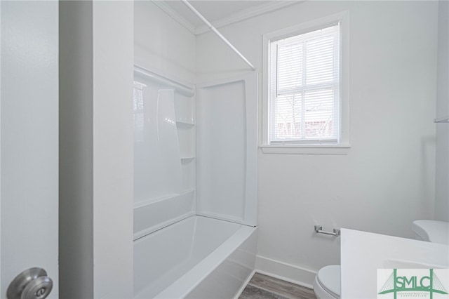 full bathroom with toilet, wood finished floors, shower / bathing tub combination, crown molding, and baseboards