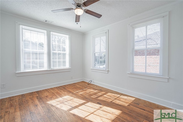 spare room featuring visible vents, ornamental molding, a textured ceiling, light wood finished floors, and baseboards