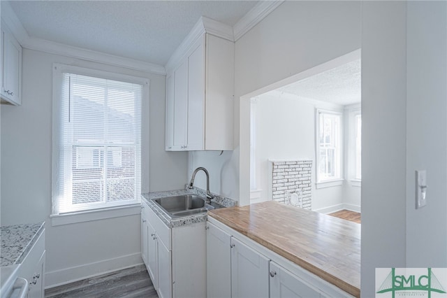 kitchen featuring dark wood-type flooring, light countertops, a textured ceiling, white cabinetry, and a sink