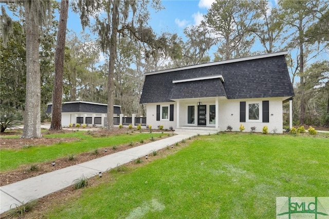 back of property with a lawn, mansard roof, a shingled roof, and stucco siding