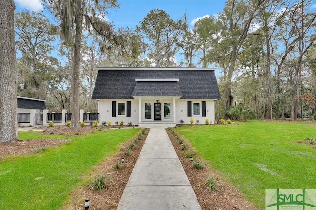 colonial inspired home featuring a front lawn, mansard roof, roof with shingles, and stucco siding