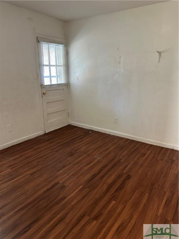 unfurnished room featuring dark wood-type flooring and baseboards