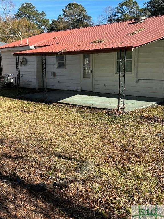 back of property with a patio, a yard, and metal roof