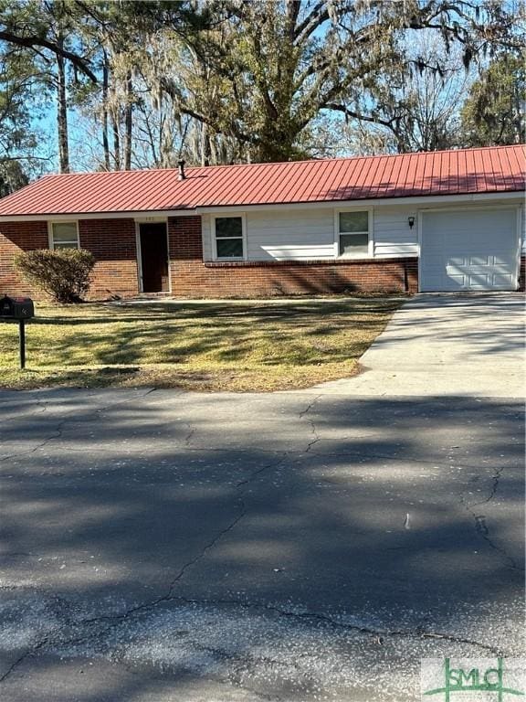 ranch-style home with brick siding, metal roof, aphalt driveway, and a garage