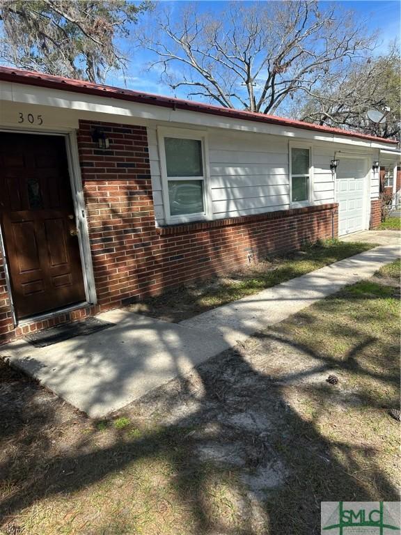 view of side of home with brick siding and an attached garage