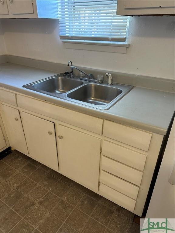 kitchen featuring white cabinetry, light countertops, and a sink