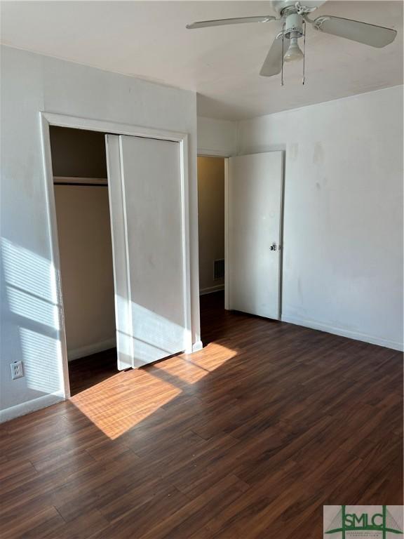 unfurnished bedroom with a closet, visible vents, baseboards, and wood finished floors