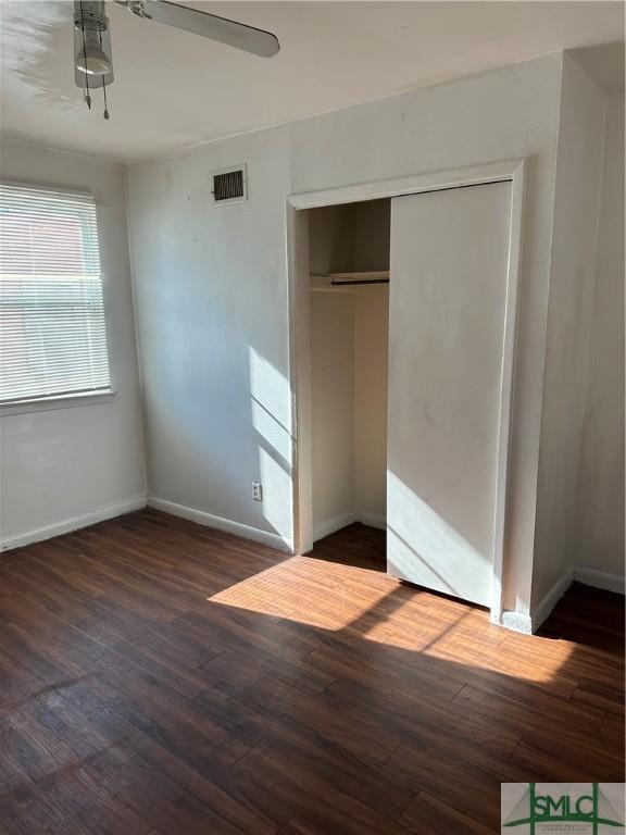 unfurnished bedroom featuring visible vents, baseboards, wood finished floors, a closet, and a ceiling fan