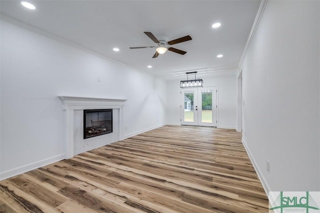 unfurnished living room with a glass covered fireplace, crown molding, recessed lighting, and light wood finished floors