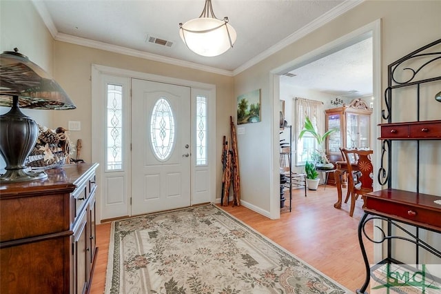 entrance foyer featuring light wood finished floors, visible vents, baseboards, and ornamental molding