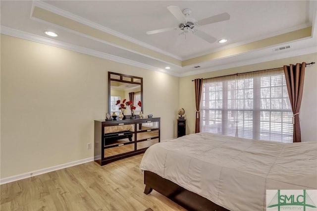 bedroom featuring a tray ceiling, light wood-style floors, visible vents, and ornamental molding