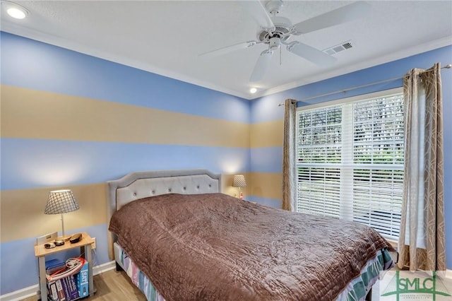 bedroom featuring baseboards, wood finished floors, visible vents, and ceiling fan