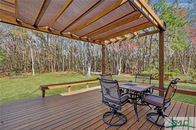 deck with a lawn, a wooded view, and outdoor dining area