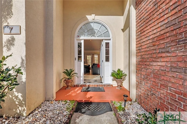 view of exterior entry with brick siding and stucco siding