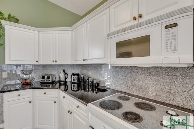 kitchen with electric cooktop, white microwave, and white cabinetry