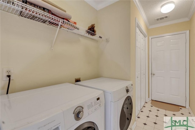 clothes washing area with visible vents, ornamental molding, a textured ceiling, laundry area, and washing machine and clothes dryer