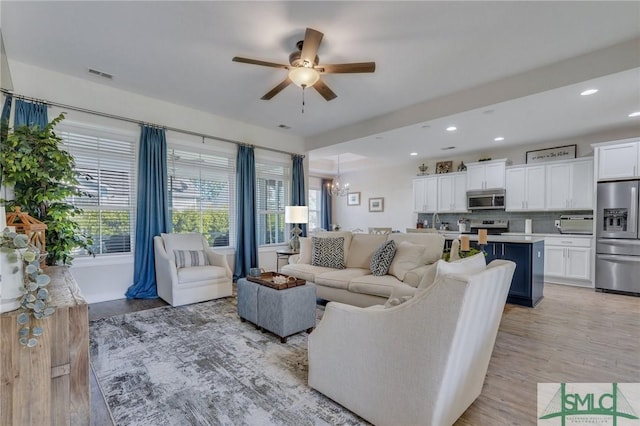 living area with recessed lighting, ceiling fan with notable chandelier, visible vents, and light wood-type flooring