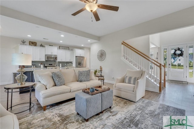 living room with light wood finished floors, baseboards, stairs, recessed lighting, and a ceiling fan